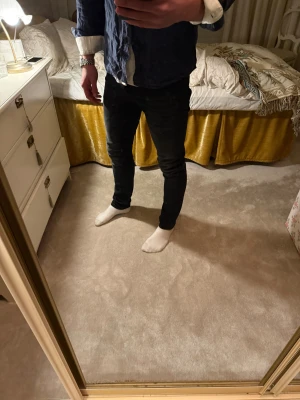 Svarta jeans storlek 29/32 - Säljer ett par svarta jeans med klassisk femficksdesign och snygga kontrastsömmar. Jeansen har en smal passform och är tillverkade i ett stretchigt jeansmaterial som sitter tajt längs benen. Perfekt för dig som gillar en modern och stilren look.