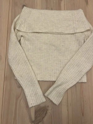 Offshoulder ribbad tröja Kappahl - Säljer en ljusbeige ribbad stickad tröja från Kappahl i offshoulder-modell. Tröjan har långa ärmar och är mjuk och skön, perfekt för kyliga dagar. Passar dig som gillar stilrena och enkla plagg med en twist.