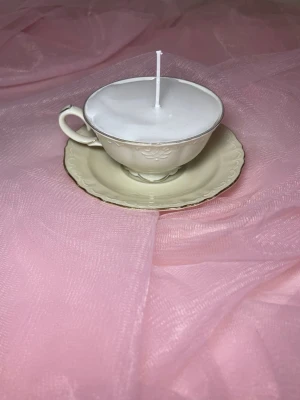 Doftljus i en tekopp i en vit färg nr 1  - Det här ljuset är gjort av återanvändbara material. Tekoppen är köpt secondhand och stearinet är från kyrkor som tänkte slänga det. Det här ljuset har en svag doft utav vanilj, så känsliga även kan använda det. Det finns även fler ljus med denna design på hemsidan, om man vill köpa sets. 