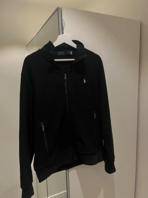 Svart Ralph Lauren fleece  - Tja, säljer denna svarta raplha luren fleecen med gult märke i storlek M, tröjan är knappt använd och har inga tecken på användning.