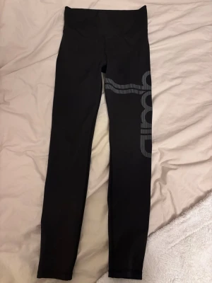 Svarta leggings med tryck från aim’n - Snygga svarta leggings från aimn med ett coolt grått tryck längs benet. Hög midja och stretchigt material som sitter skönt och följer kroppen. Perfekta för träning eller chill. Materialet är troligtvis polyester eller syntet för bästa komfort.