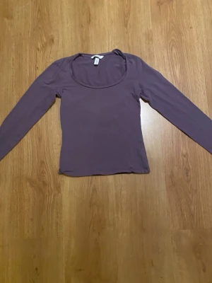 Lila långärmad topp med rund hals - Säljer en enkel och stilren lila långärmad topp med rund halsringning. Toppen har en slim passform och är tillverkad i mjukt material som känns skönt mot huden. Perfekt att matcha med jeans eller kjol för en avslappnad look.