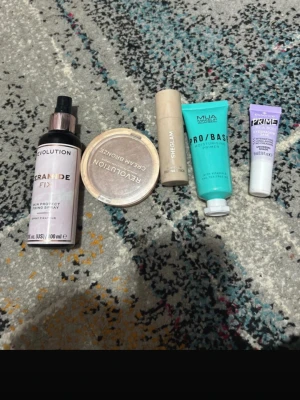 Sminkpaket med bronzer, primer & stick - Säljer ett sminkpaket med Revolution Ceramide Fix face mist (100 ml), Revolution Cream Bronzer i rund dosa, SHEGLAM Snatch Defining Stick i brun ton, MUA Pro/Base fuktgivande primer i turkos tub och Essence Prime Like A Boss ögonskuggsprimer i lila tub.