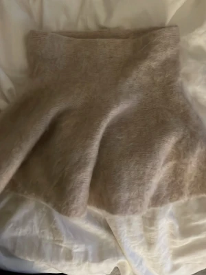 Beige stickad polotröja - Mysig beige kjol i stickat material med fluffig yta. Perfekt för kyliga dagar och enkel att matcha med olika outfits. ger en extra skön känsla och kjolen har en avslappnad passform.