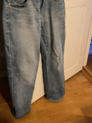 Levi's Loose Taper ljusblå jeans - Ljusblå jeans från Levi's i loose taper-modell. Jeansen har en avslappnad passform med avsmalnande ben och klassisk femficksdesign. Materialet är slitstarkt jeans och det finns en liten reva på ena benet för en extra casual vibe.