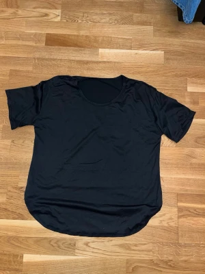Svart basic t-shirt - En enkel svart t-shirt med rund hals och korta ärmar. Modellen är loose fit och har en lätt rundad nederkant. Perfekt att matcha med jeans eller shorts för en clean look.