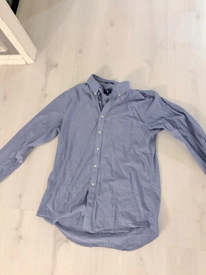 Blå skjorta från GANT i bomull XL - Snygg blå skjorta från GANT i storlek XL. Klassisk button-down krage, vita knappar och bröstficka med liten logga. Tillverkad i bomull
