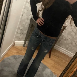 Blå bootcut jeans från Diesel - Snygga blå jeans från Diesel med bootcut passform och slitna detaljer för en cool vibe. Jeansen har låg midja och dragkedja i gylfen. Materialet är robust denim med tydliga slitningar och tvättade effekter. En knapp saknas som kan ses på bild 4 men man merker inte av det överhuvudtaget.