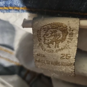 Blå jeans från Miss Sixty, storlek 25 - Snygga ljusblå jeans från Miss Sixty med slitningar och snygg tvätt. Klassisk femficksmodell med dragkedja och knapp framtill, samt dekorativa sömmar på bakfickorna. Jeansen har en smal passform och är tillverkade i bomull med lite stretch.