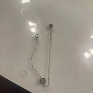 Silvrigt armband med sten från Edblad - Snyggt armband i silverfärg från Edblad med tunn kedja och en rund, glittrande sten i mitten. Liten bricka med Edblads logga vid låset. Perfekt för dig som gillar stilrena smycken med en touch av bling.