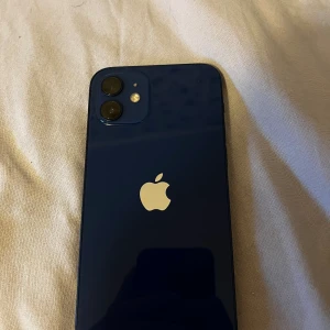 iPhone 12 - Snygg blå iPhone 12 med dubbla kameror och 84% batterihälsa. Telefonen är i gott skick utan synliga repor eller skador på skärm eller baksida. Perfekt för dig som vill ha en pålitlig och stilren mobil med bra prestanda och kamera skriv för mer info eller bilder!