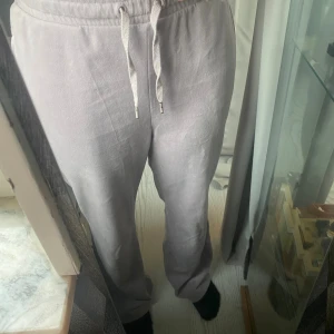 Lila mjukisbyxor från H&M  - Säljer ett par ljuslila mjukisbyxor från H&M i storlek XS. Byxorna har normal passform, raka ben och snörning i midjan. Materialet är mjukt och skönt, perfekt för chill dagar. Fickor på sidorna och elastisk midja för extra komfort.