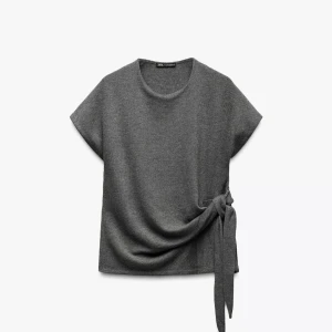 Grå topp från zara - Säljer en aldrig använd grå stickad t-shirt ifrån Zara. Fin knytdetalj💕 Prislappen är inte kvar tyvärr.