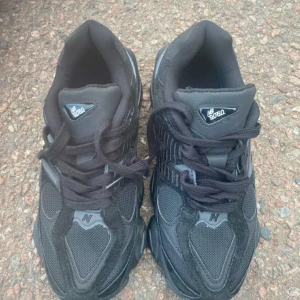 New Balance 9060 svarta sneakers - Säljer ett par svarta New Balance 9060 sneakers med chunky sula och meshdetaljer. Skorna har snörning, mockapartier och coola former på sulan. Perfekta för dig som gillar streetwear och vill ha en modern look.