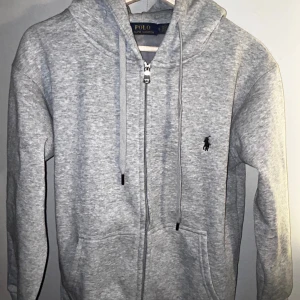 Grå hoodie från Polo Ralph Lauren - Jag säljer min Ralph lauren fleese hoodie för att jag tyckte den var för liten för mig. Står S men kan vara lite mer åt XS. Den är skitbekväm och jättegrisch. Om ni har några frågor tveka inte att meddela och priset ar ej hugget i sten