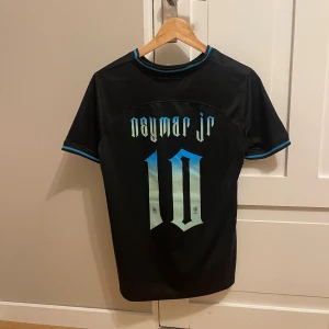 Svart Neymar Jr Brasilien Nike tröja - Säljer en svart Brasilien fotbollströja från Nike med Neymar Jr och nummer 10 i blått och vitt på ryggen. Tröjan har korta ärmar, blå detaljer vid krage och ärmslut samt Brasilien-emblem på bröstet. Tillverkad i Dri-Fit material som andas.