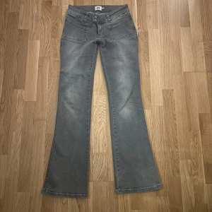 Grå bootcut jeans från 157 Paris Patch - Grå jeans från 157, modell Paris Patch, i bootcut-stil med full längd. Byxorna har framfickor med patch-detalj och klassiska bakfickor. Snygg tvättad grå färg och tillverkade i bomullsmix för en skön känsla. Använda några få gånger, fint skick!