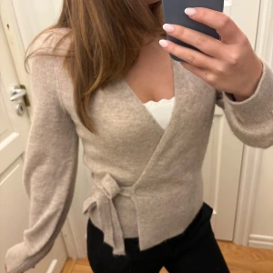 Beige omlottkofta  - Säljer denna fina kofta pga att den inte kommer till användning, den är helt ny och aldrig använd!! Nypris 790❤️