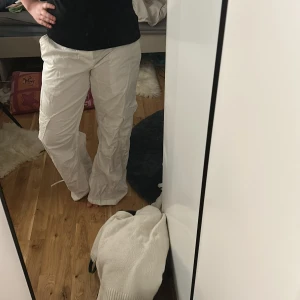 Vita cargopants med snörning - Säljer ett par vita cargopants med bred passform och snörning i midjan. Byxorna har stora fickor på sidorna och är tillverkade i ett lätt material som känns skönt mot huden. Perfekta för dig som gillar en avslappnad och cool stil. Köpa på Gina för 500, prislapp finns kvar, ej använda 