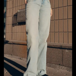 Lågmidjade zara jeans - Säljer ett par ljusblå jeans från Zara med klassisk femficksdesign och raka ben. Jeansen har hög midja och är tillverkade i mjukt denimtyg. Perfekt för dig som gillar en avslappnad och stilren look.