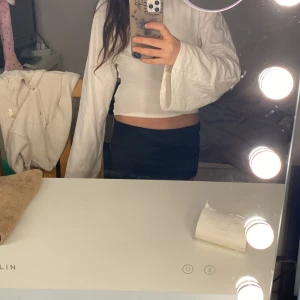 Vit croppad omlottopp med knyt från 157 - Säljer en vit croppad topp från lager 157 med långa ärmar och snygg knytning i ryggen. Toppen har omlottdetalj bak som ger en öppen rygg och cool look. Tillverkad i mjuk bomull, perfekt för dig som gillar stilrena och trendiga plagg. Inte andvända många gånger och säljer för att ärmarna är lite för långa för mig 💕på bilden ser den lite skrynklig ut men de är för att den var presic tvättad💕