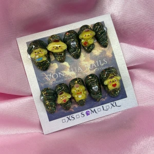 PompompurinSet(M);Short Almond;Curved - Handgjorda press on-naglar med mörkgrön bas, guldglitter och 3D Pompompurin-figurer i gult. Naglarna har en kort mandelform och dekoreras med små hjärtan och detaljer i rött, silver och blått. Perfekt för dig som vill ha unika och söta naglar med Sanrio-tema.M: 16 mm, 12 mm, 12,5 mm, 11,5 mm, 10 mm