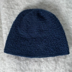 Mörkblå virkad mössa - Virkad mössa i mörkblått. Mössan har en klassisk form som sitter skönt på huvudet och är gjort i alpacka garn!