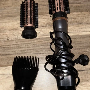 Varmluftsborste med tillbehör - Multifunktionell varmluftsborste med två rundborstar och en kamtillbehör. Perfekt för att styla och torka håret samtidigt. Produkten ser ut att vara i gott skick med minimalt slitage. Sladd och kontakt är intakta.