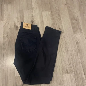 Svarta jeans från Morris, 29/32 - Svarta jeans från Morris med snygg broderad logga på bakfickan och detaljerade nitar. Klassisk femficksmodell med rak passform och stilren look. Jeansen är gjorda i mjukt bomullsmaterial med en skön stretch som gör dem bekväma hela dagen.