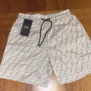Beige Fendi shorts - Snygga shorts från Fendi i beige och vitt med ikoniskt FF-logomönster över hela tyget. Helt nya, oanvända. Storlek M, passar S.