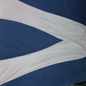 Ljusrosa mjukisbyxor med strassdetalj - Supermjuka ljusrosa mjukisbyxor med bootcut-ben och snörning i midjan. Byxorna har fickor och en snygg strassdetalj i form av ett T på ena benet. Perfekta för chill dagar eller när du vill vara extra comfy.