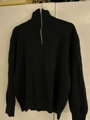 Svart stickad half zip-tröja från Zara - Svart stickad tröja från Zara med hög krage och silverfärgad half zip-dragkedja. Tröjan har lång ärm och en clean, minimalistisk look som passar perfekt till lager-på-lager-stil. Skön och mjuk känsla, perfekt för kyligare dagar.