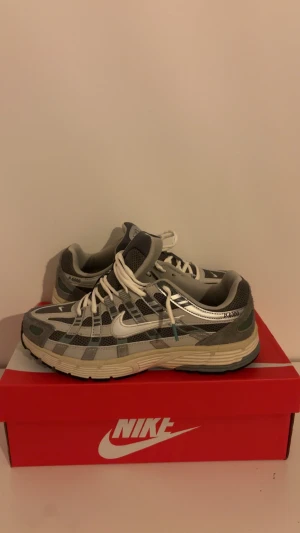 Nike P-6000  - Nike P-6000 sneakers i grå och silver med vita detaljer och snörning. Finns i både 42 och 43