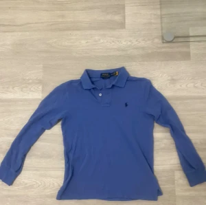 Blå långärmad pikétröja Polo Ralph Lauren - Snygg blå långärmad pikétröja från Polo Ralph Lauren med klassisk krage och två knappar framtill. Tröjan är storlek xs. Den har inga defekter eller hål. Priset går att diskuteras vid snabbaffär. Om du vill ställe frågor höra av mig.