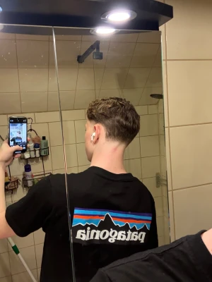 Svart Patagonia t-shirt med tryck - Svart t-shirt från Patagonia med stort färgglatt logotryck på ryggen och mindre logga på bröstet. Dunder skick, fraktas samma dag som köp 