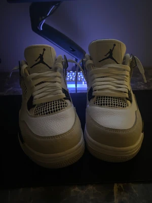 Nike Air Jordan 4 Retro White/Black - Säljer ett par Nike Air Jordan 4 Retro i färgen vit, svart och grå. Skorna har klassisk mesh och skinn på ovandelen, ikonisk Jumpman-logga på plösen och sulan samt coola detaljer i svart. Perfekta för dig som vill sticka ut med en tidlös sneaker.