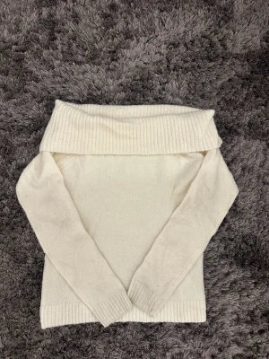 Offshoulder stickad tröja Gina Tricot - Supermysig offshoulder stickad tröja från Gina Tricot i krämvit färg. Tröjan har bred ribbad kant upptill och vid ärmslut, samt långa ärmar. Perfekt för dig som gillar en chill och stilren look.