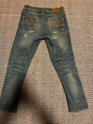 Nudie Jeans blå  - Säljer ett par blå jeans från nudie som har sköna slitningar och riktigt skön passform och trendiga just nu! Skriv vid frågor osv