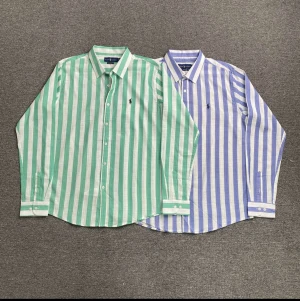 Grön- och vitrandig skjorta Ralph Lauren - Klassisk grön- och vitrandig skjorta från Ralph Lauren i luftig linnemix. Skjortan har lång ärm, knappar framtill och broderad logga på bröstet. Perfekt oversized vibe och snygg krage för en clean look. 1 st kostar 850kr pris kan ej sänkas 