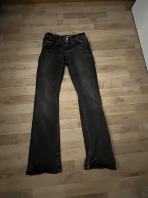 Svarta bootcut jeans Gina Tricot 164 - Svarta jeans från Gina Tricot i storlek 164. Modellen har bootcut-ben, klassiska fem fickor och dubbla knappar i midjan. Snygga kontrastsömmar och lätt tvättad look. Perfekta för dig som gillar en tidlös och cool stil.