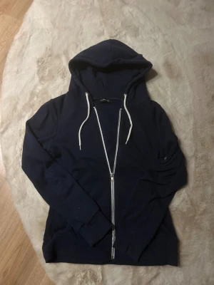 Mörkblå zip hoodie med vita band  - Mörkblå zip som är i väldigt fint skick, säljer då jag inte använder den