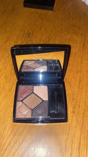 Dior 5 Couleurs ögonskuggspalett - Snygg ögonskuggspalett från Dior i färgen 797 Feel med fem nyanser i brunt, beige, guld och mörkbrun. Kommer i en lyxig svart dosa med spegel och applikator. Perfekt för att skapa både mjuka och intensiva ögonlooks.
