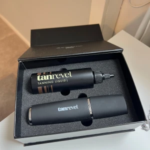 Tanrevel Tanning Liquid Kit - Den innehåller apparaten, vätskan och en laddare. Om vätskan är gammal kan man bara köpa ny. Apparaten är knappt använd och fungerar som ny. 