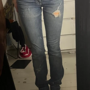 Blå bootcut jeans från Pinko - Snygga blå jeans från Pinko med bootcut passform och slitna detaljer framtill. Jeansen har coola bakfickor med vit kontrastsöm och klassisk femficksdesign. Materialet är jeans med en skön känsla och de har låg midja. Perfekta för dig som gillar en avslappnad men trendig look.