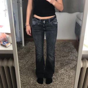 Mörkgrå bootcut jeans med låg midja - Snygga mörkgrå jeans med bootcut och låg midja. Jeansen har klassiska fem fickor, markerade sömmar och en lätt tvättad look. Perfekta för dig som gillar en avslappnad men trendig stil.