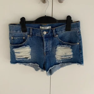 Blå jeansshorts  - Säljer ett par blå jeansshorts från Bik Bok i klassisk femficksmodell. Shortsen har slitna detaljer framtill, fransig nederkant och normal passform. Perfekta för sommaren och ger en cool, avslappnad vibe.🩷💘