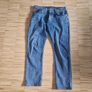 Blå jeans från East West Regular Fit - Säljer ett par klassiska blå jeans från East West i regular fit. Jeansen har fem fickor, raka ben och snygga kontrastsömmar. Perfekta för dig som gillar en tidlös och enkel stil. Materialet är slitstarkt jeans och färgen är en mellanblå tvätt. Storlek är W34 L32
