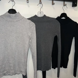 Tre polotröjor i neutrala färger - 240kr, för alla tre tröjor. Tre stilrena polotröjor i ljusgrått, mörkgrått och svart. Alla har lång ärm och hög krage, perfekta för lager-på-lager. Den ljusgrå är ribbstickad medan de andra är släta. Snygga basplagg som funkar till allt.