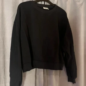 Svart sweatshirt från Pull&Bear - En svart, basic sweatshirt från Pull&Bear i storlek M. Tröjan har rund halsringning, långa ärmar och en avslappnad passform. Tillverkad i mjuk bomullsblandning som är skön att bära. Perfekt för en chill och stilren look.
