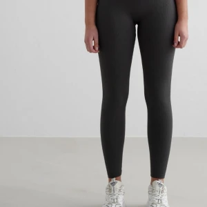 Gråa ribbade leggings med hög midja - Snygga svarta leggings med ribbad struktur och hög midja. De är tighta och stretchiga, perfekta för en sportig look eller chill outfit. Diskret logga framtill vid midjan. Använda någon gång och är i nytt skick. Priset kan diskuteras och de är storlek M🫶🏽🫶🏽 från Aimn 